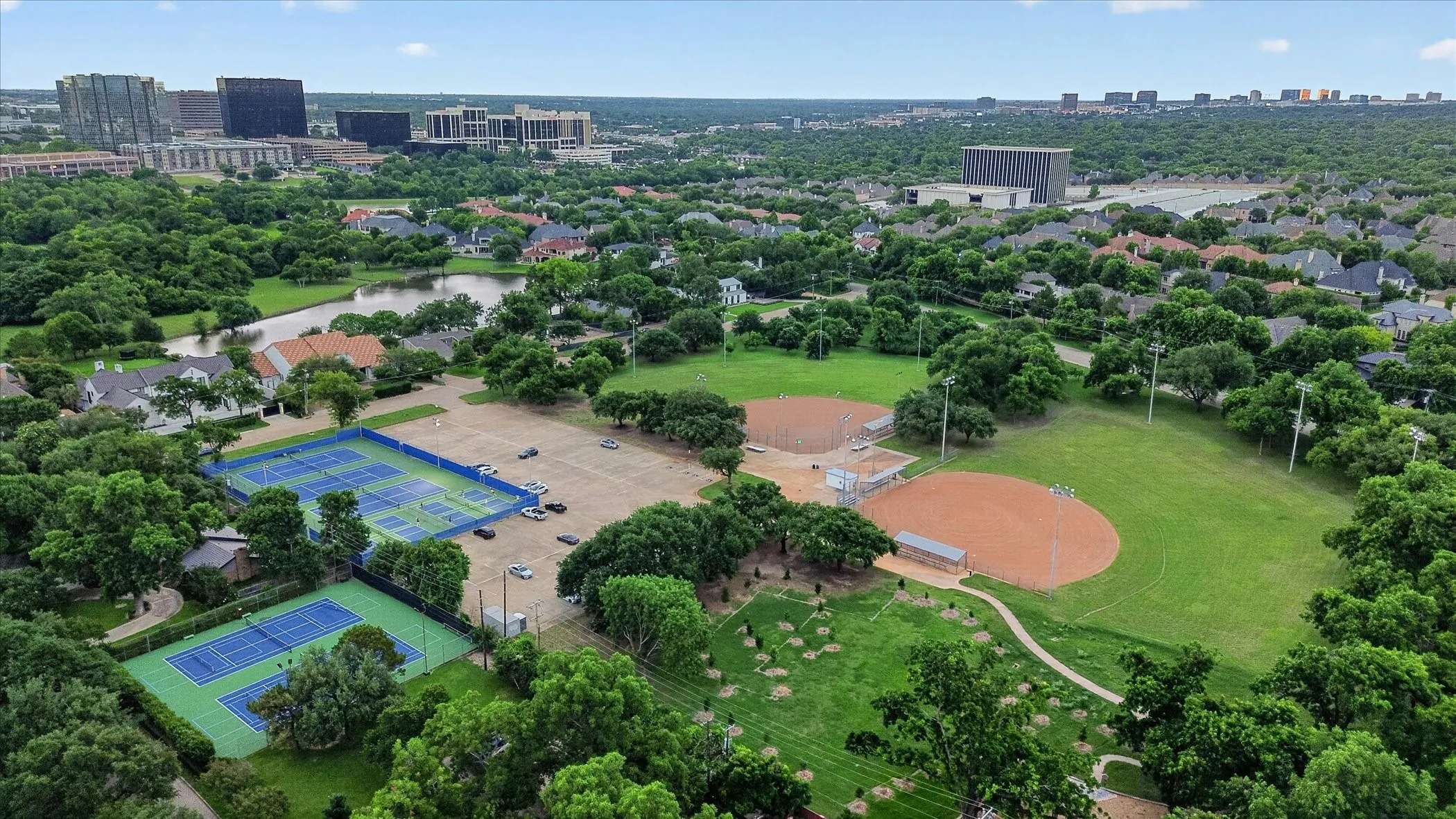 Aerial perspective showcasing extensive green spaces, multiple tennis courts, and two baseball diamonds