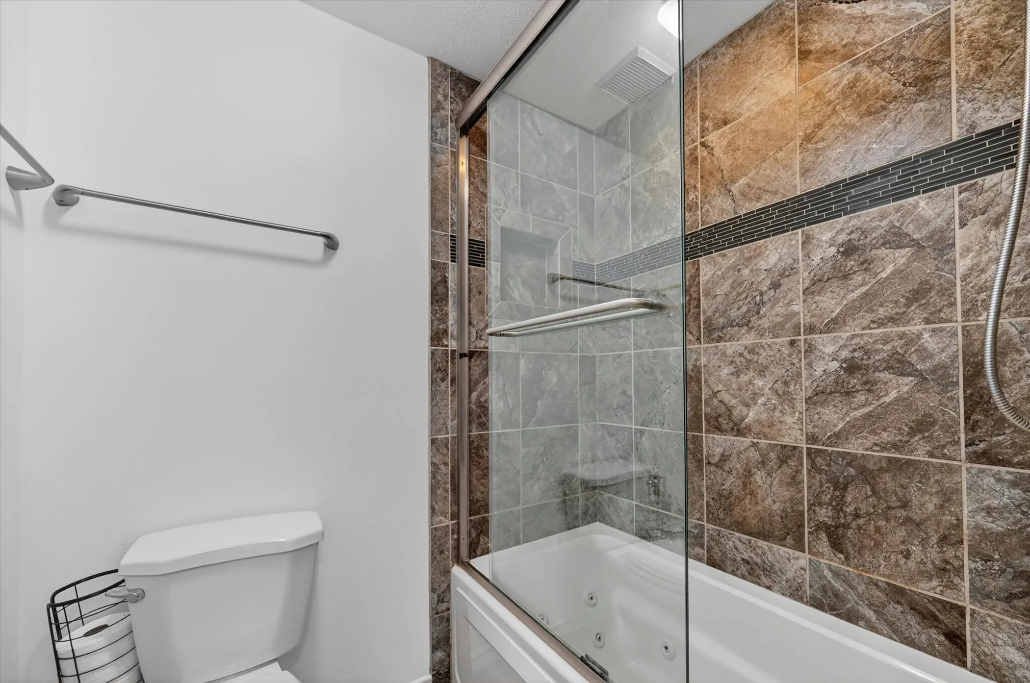Full bathroom featuring a shower-tub combination with sliding glass doors, built-in tub jets, and a tiled surround