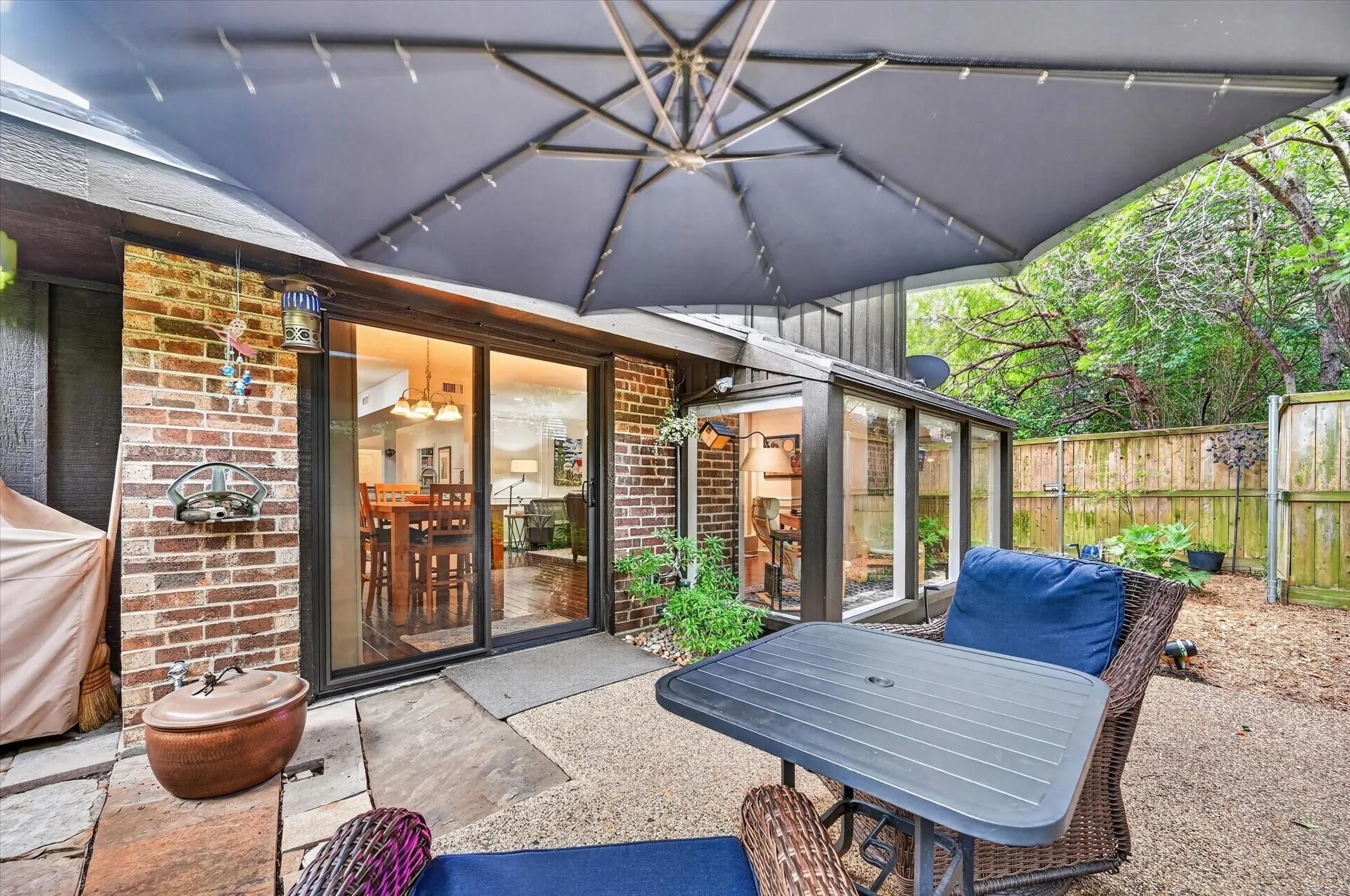 Outdoor patio featuring natural stone pavers, a gravel surface, brick siding, and a fenced perimeter