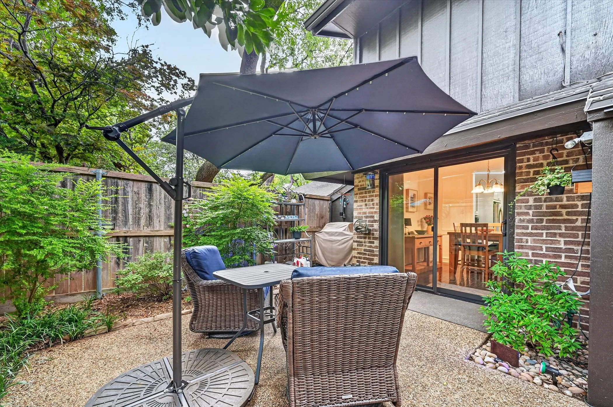 Private outdoor patio featuring a gravel surface, brick exterior, and a sliding glass door for interior access