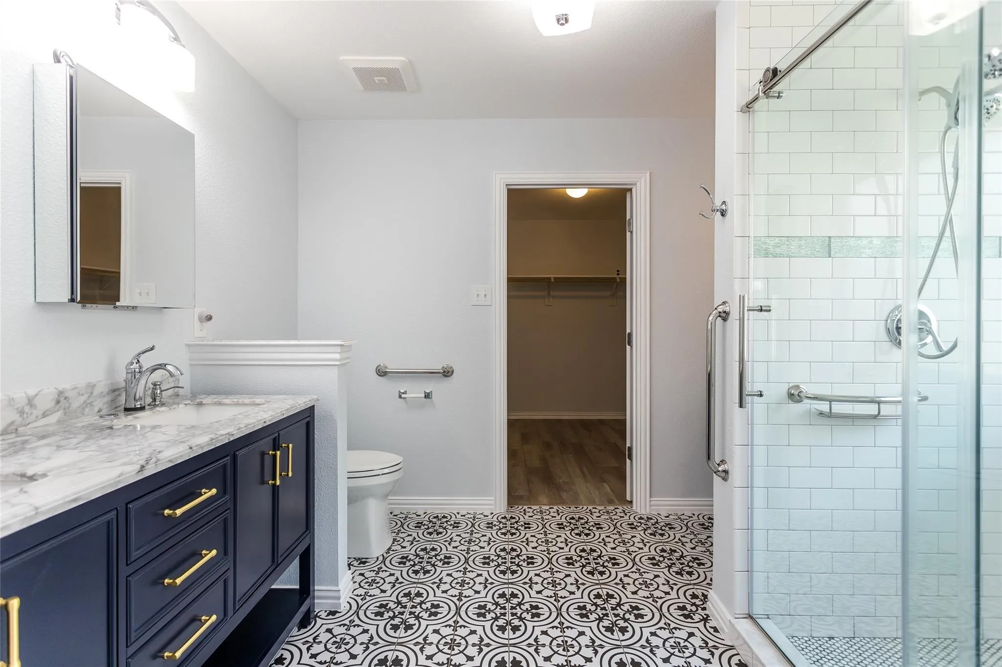Bathroom with a stall shower, vanity, and a walk in closet