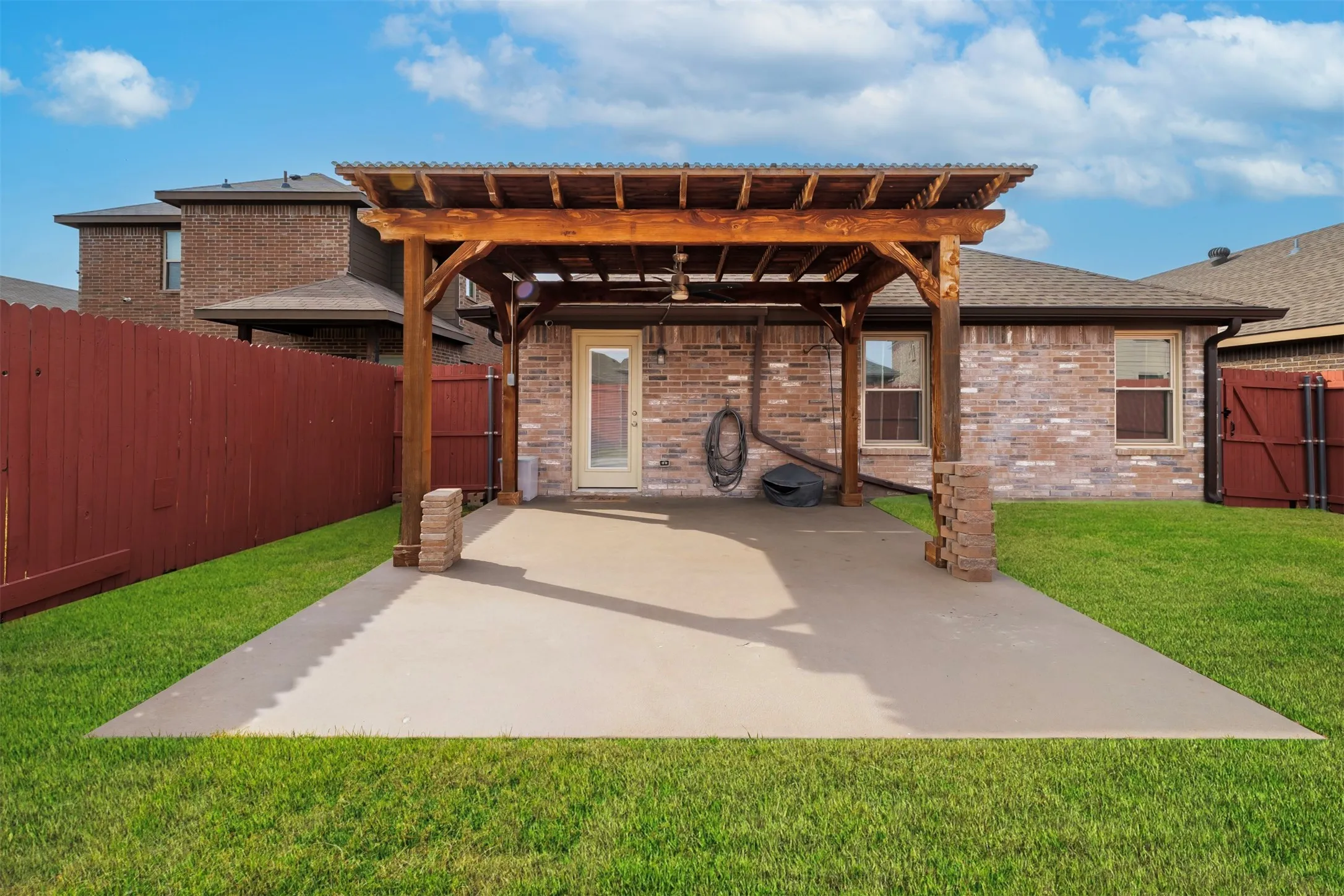 Rear view of house with a gate, a fenced backyard, a patio area, a pergola, and brick siding
