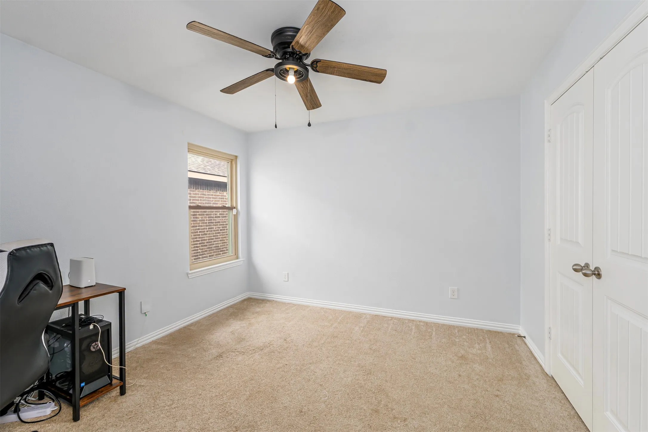 Unfurnished bedroom featuring light carpet, ceiling fan, a closet, and an office area