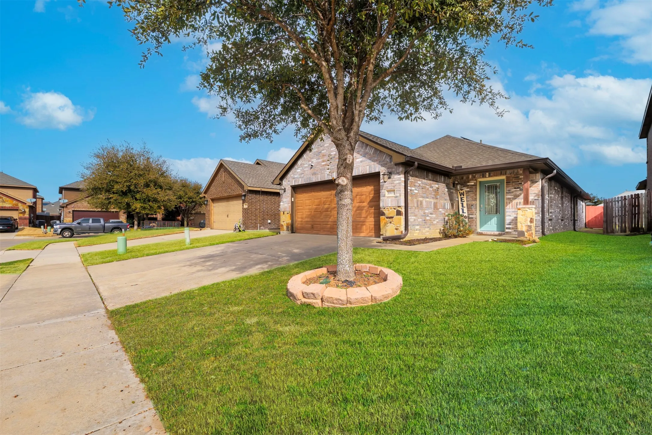 Ranch-style home featuring concrete driveway, brick siding, an attached garage, and a residential view