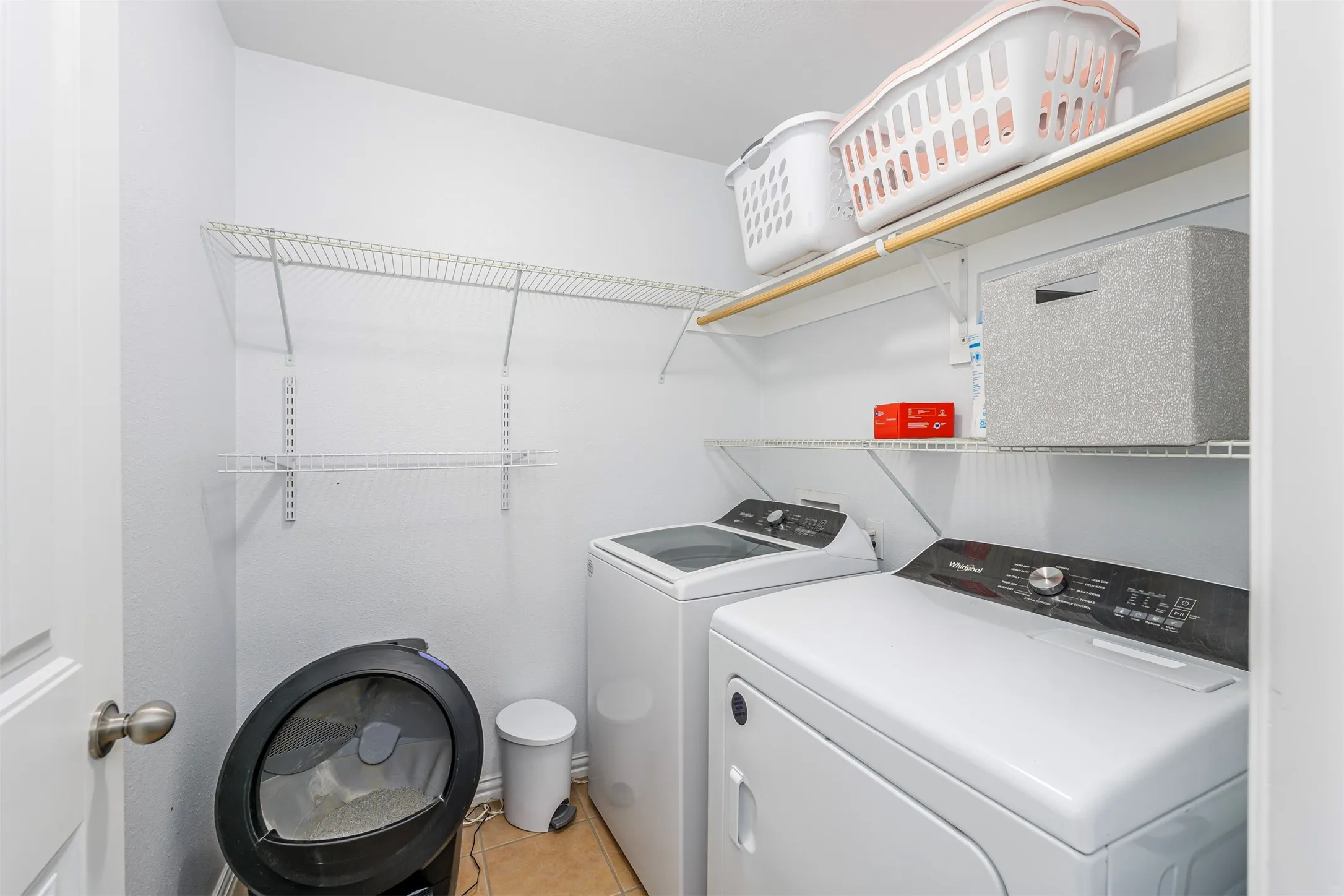 Laundry area with independent washer and dryer and light tile patterned floors