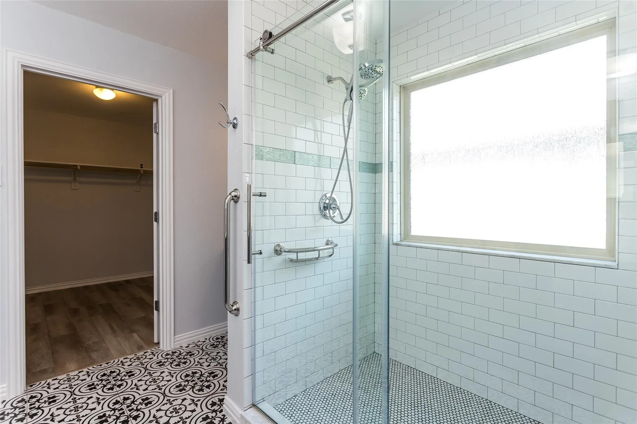 Bathroom featuring a spacious closet, a shower stall, and tile patterned floors