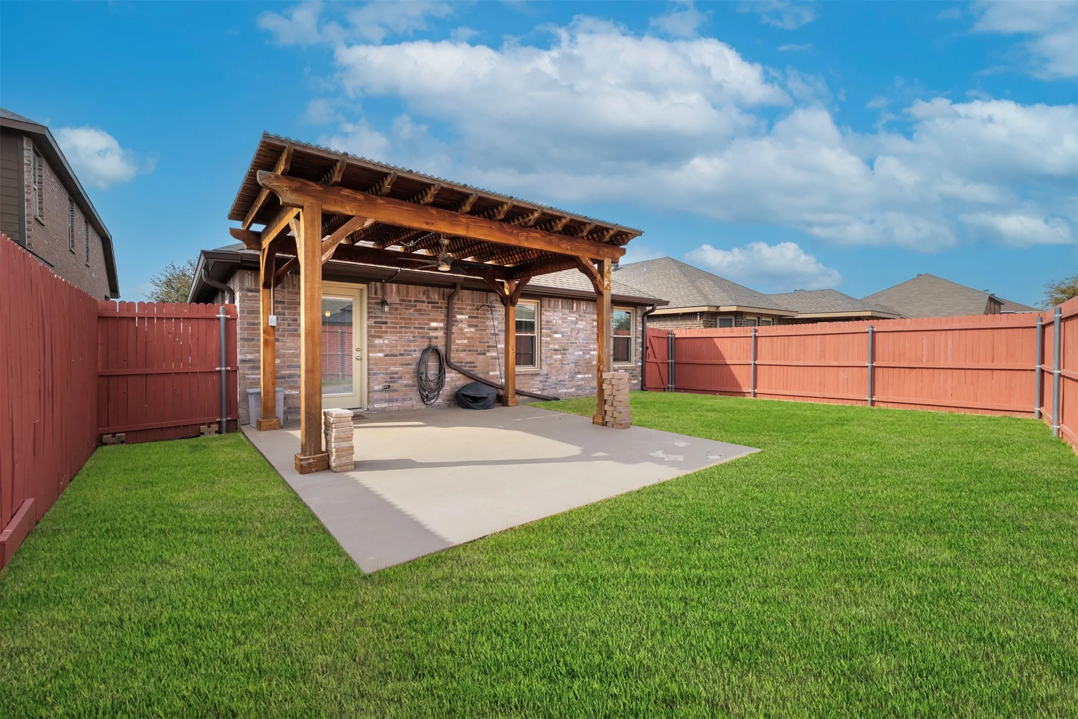 Back of property with a pergola, a fenced backyard, a patio, and brick siding