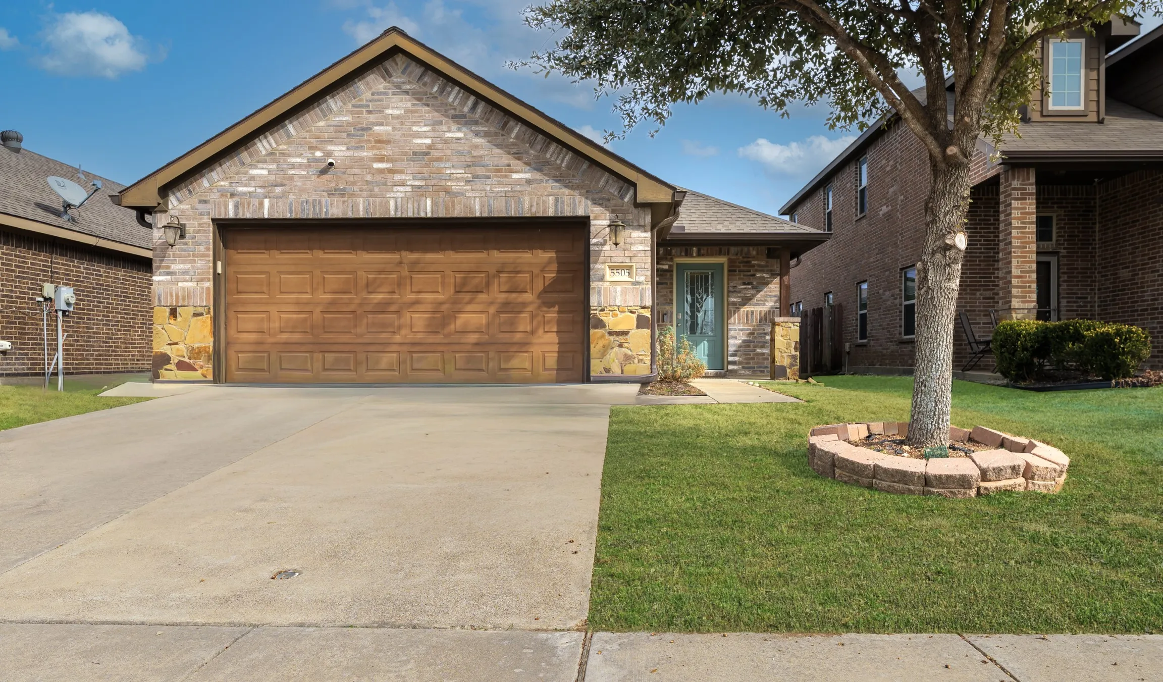 View of front of home with a front lawn, driveway, brick siding, and an attached garage