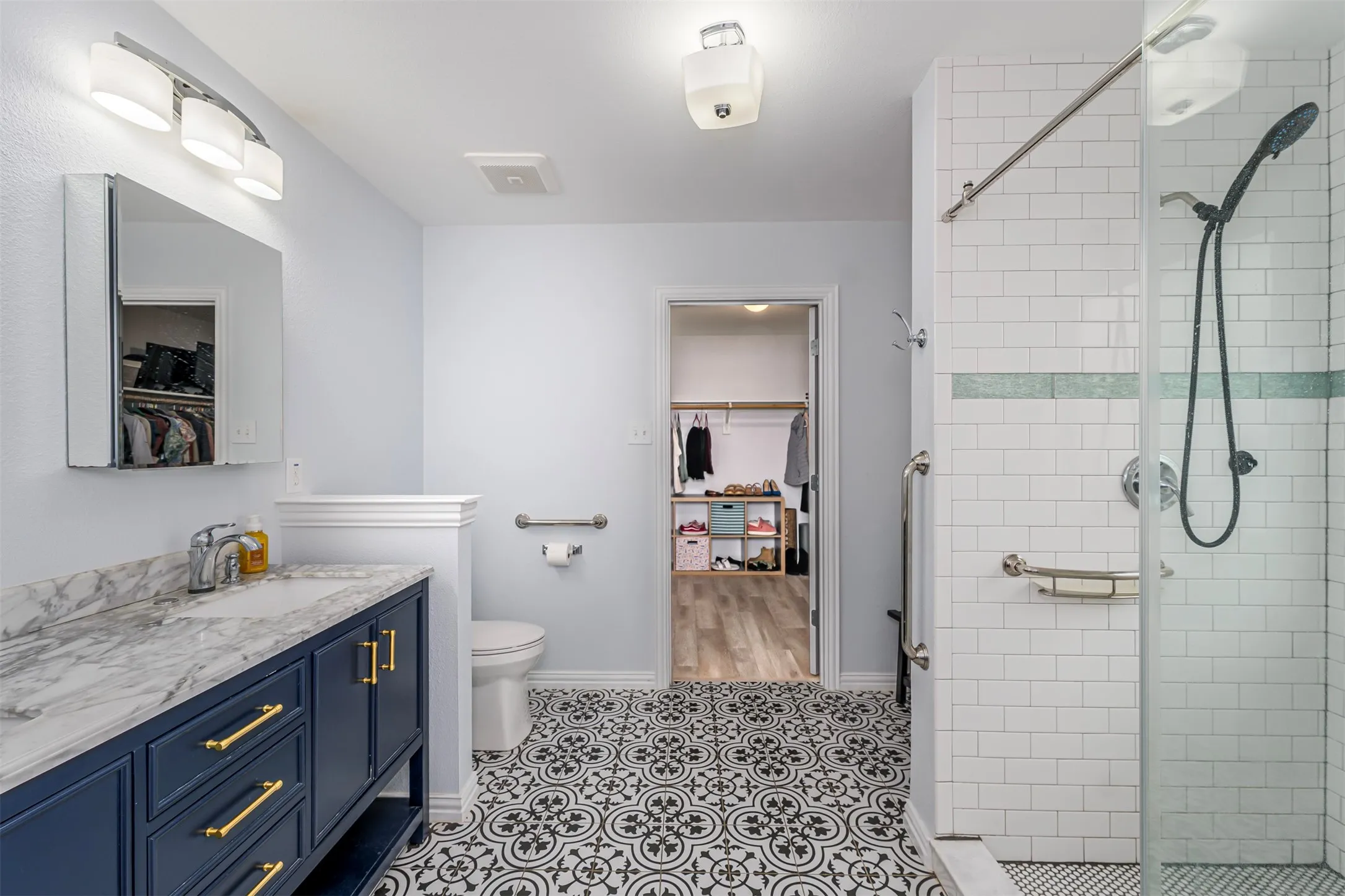 Full bath with a walk in closet, a shower stall, vanity, and light tile patterned floors