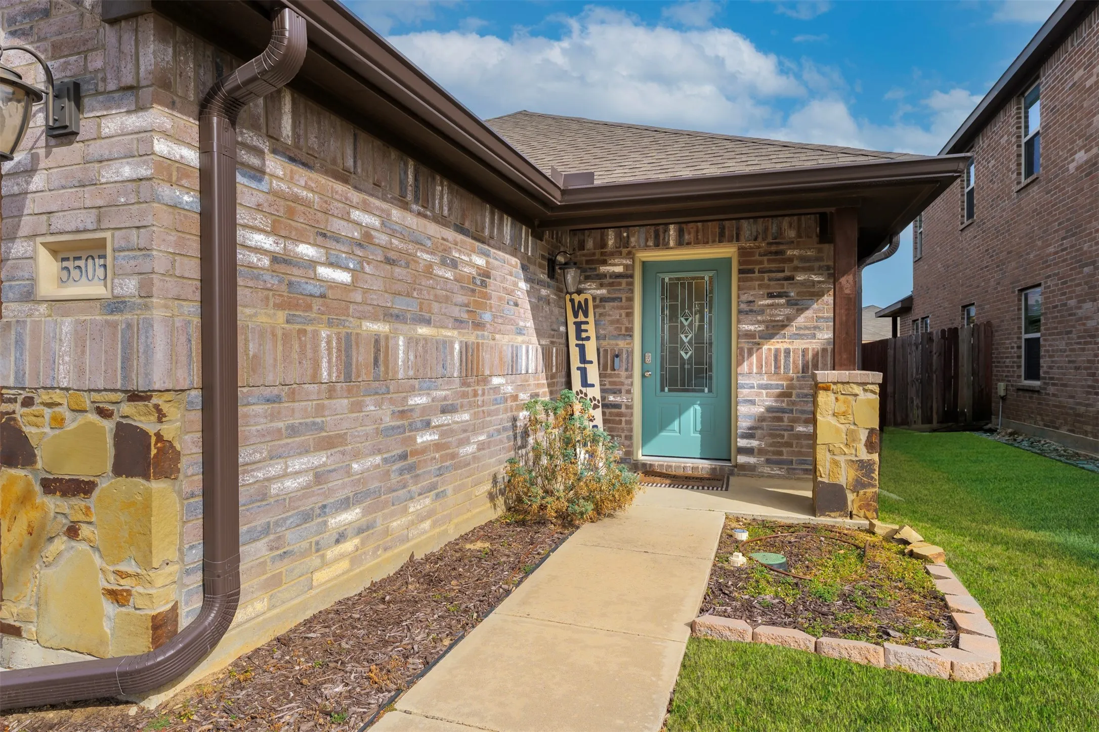 Property entrance with brick siding, a shingled roof, and stone siding
