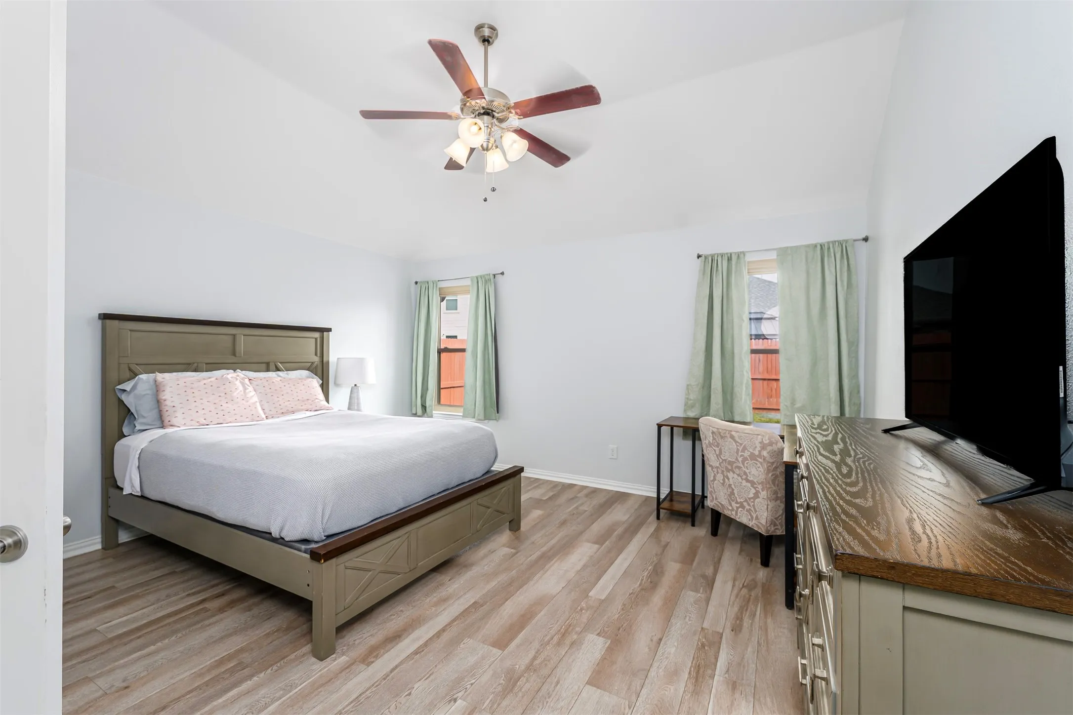 Bedroom with light wood finished floors, lofted ceiling, and ceiling fan