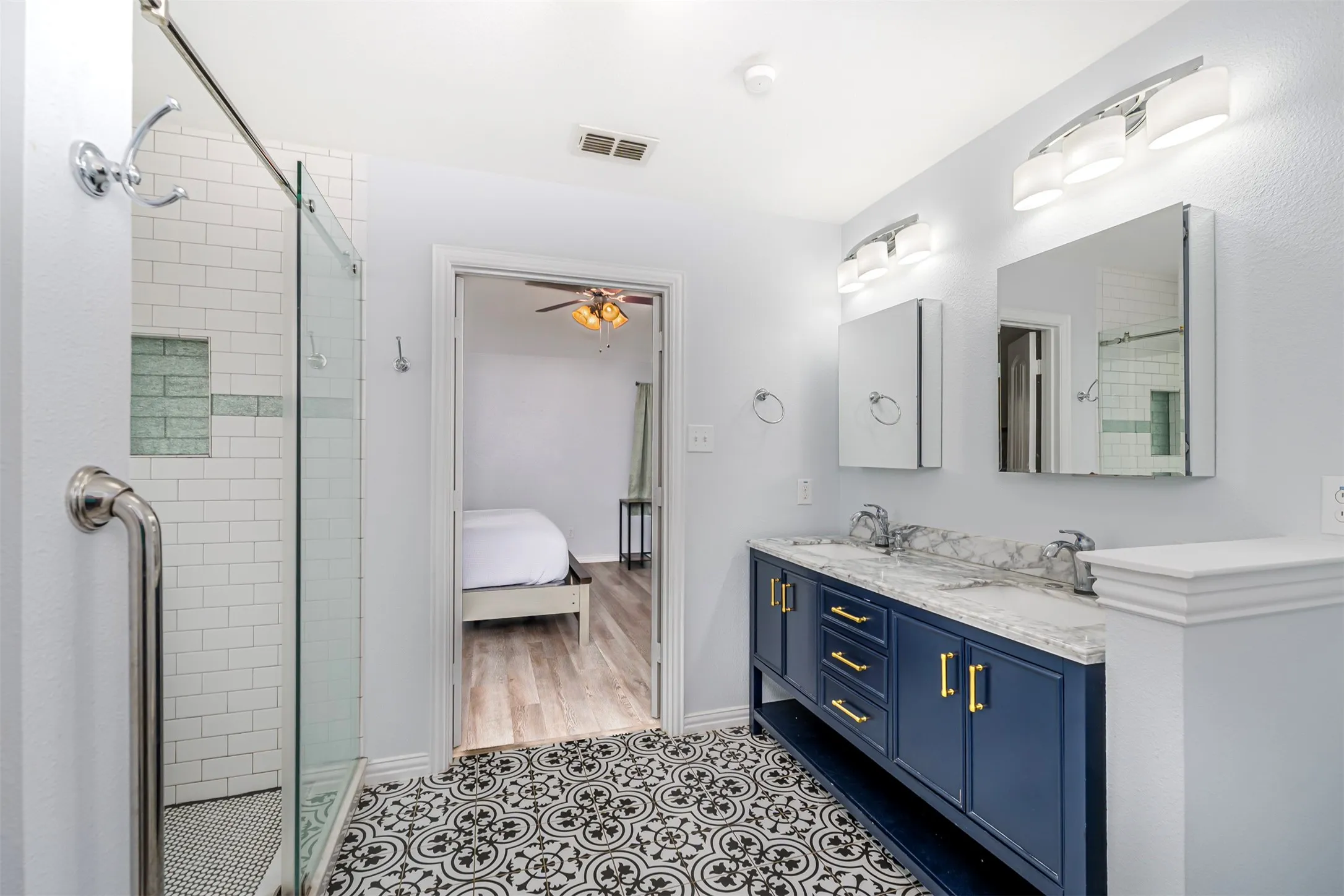 Full bath with a shower stall, double vanity, a ceiling fan, and ensuite bath