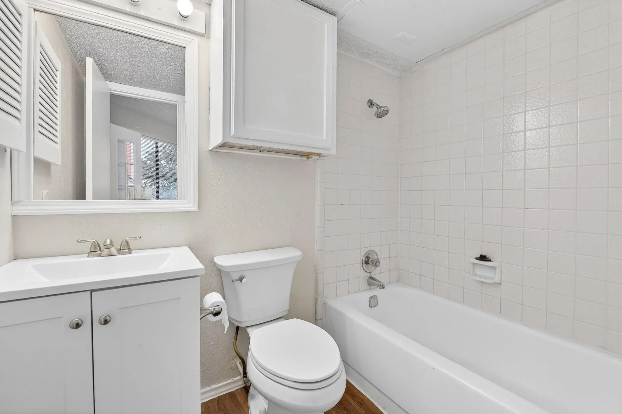 Bathroom featuring a white vanity with integrated sink, chrome faucet, and framed mirror