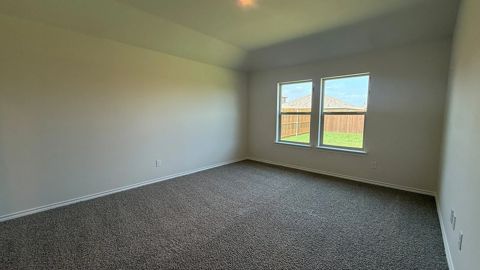 Spacious room featuring neutral carpeting, light-colored walls, and a tray ceiling