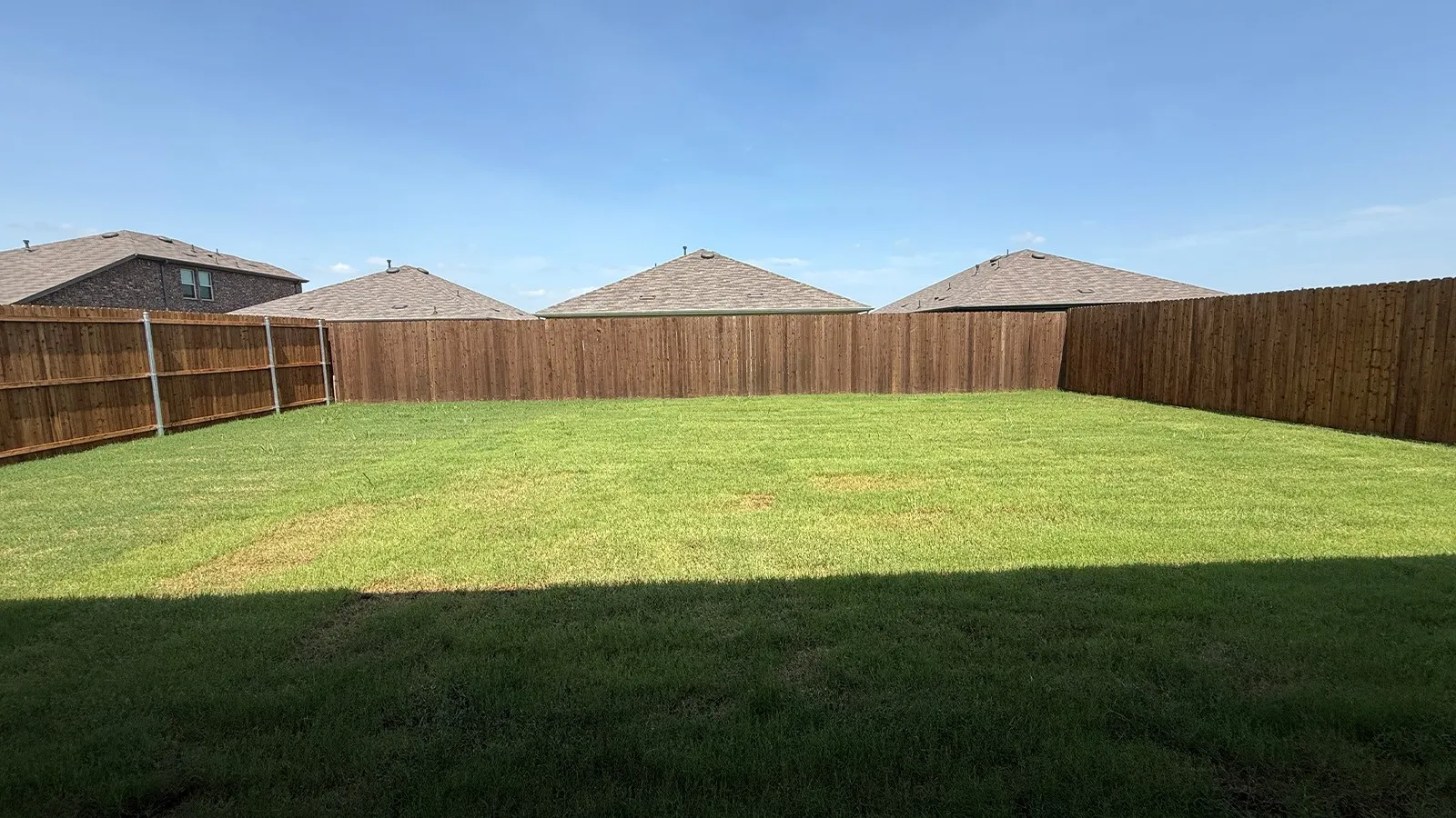 Expansive private backyard featuring a level lawn and perimeter wood fencing