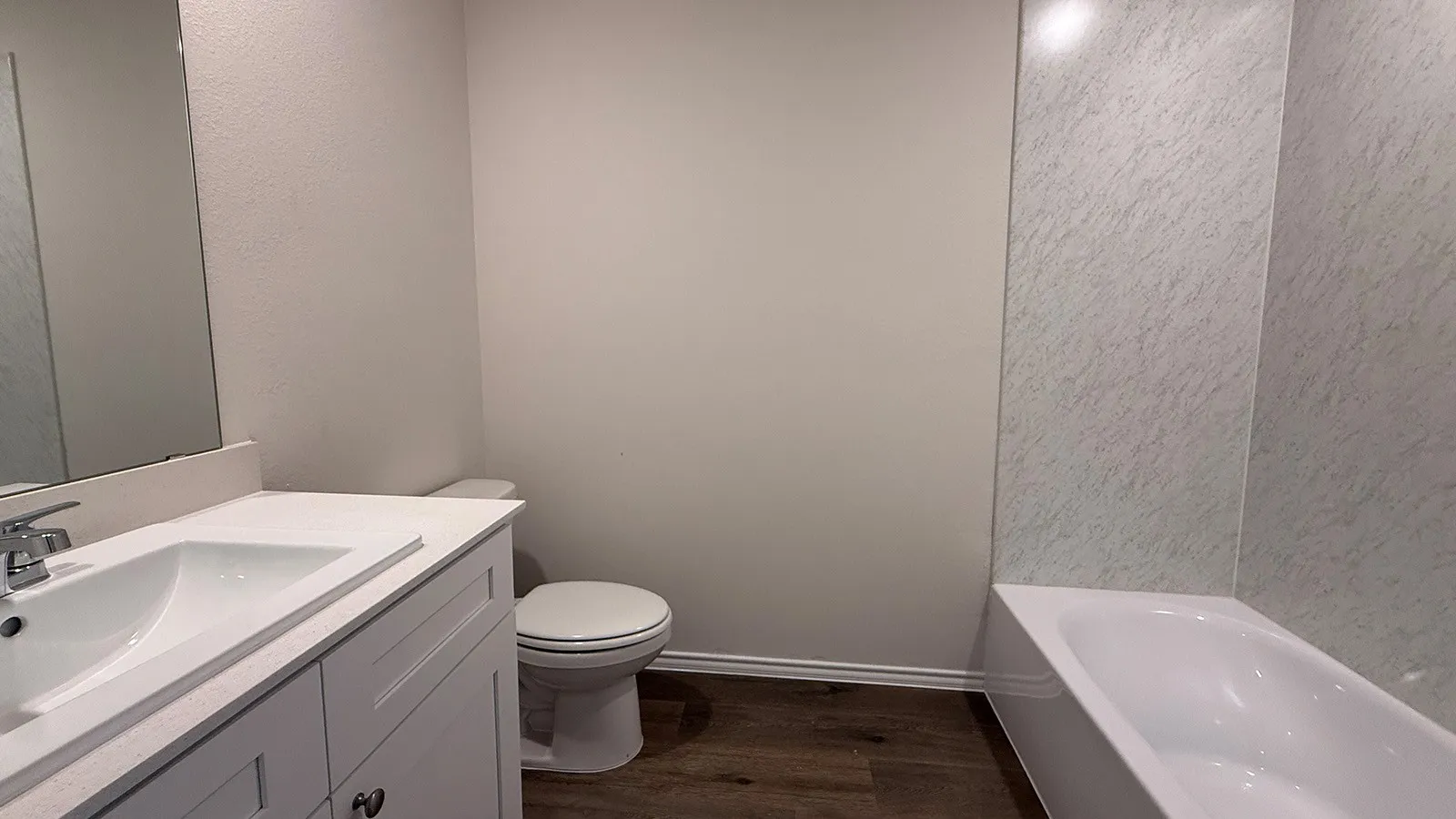 Bathroom featuring a white vanity with integrated sink, chrome faucet, and a large mirror