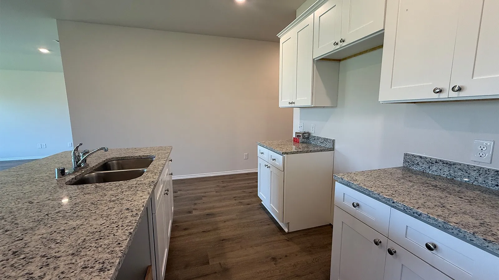 Kitchen featuring granite countertops, wood-finish flooring, white cabinetry, a double basin sink, and recessed lighting