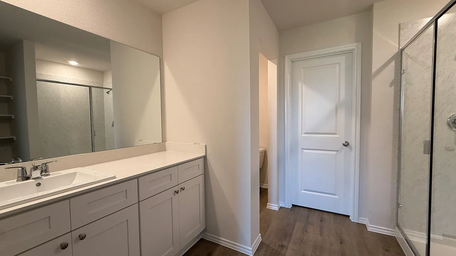 Bathroom vanity featuring a quartz countertop, integrated sink, and white shaker-style cabinetry