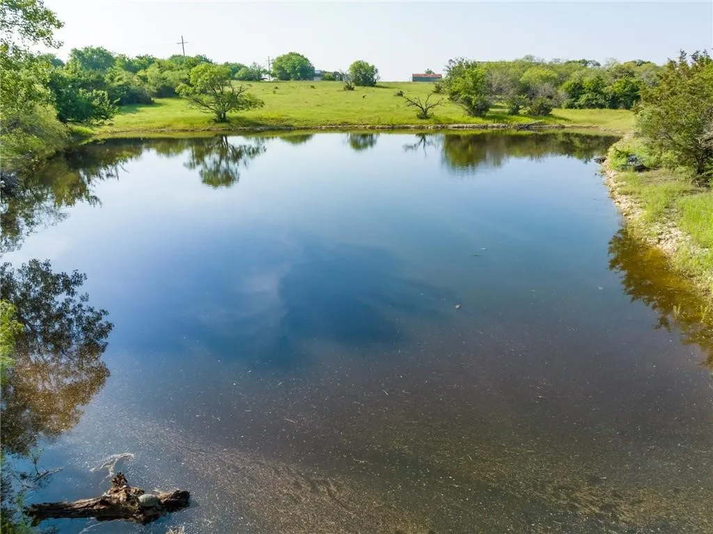 Expansive pond feature surrounded by green pastures and mature trees