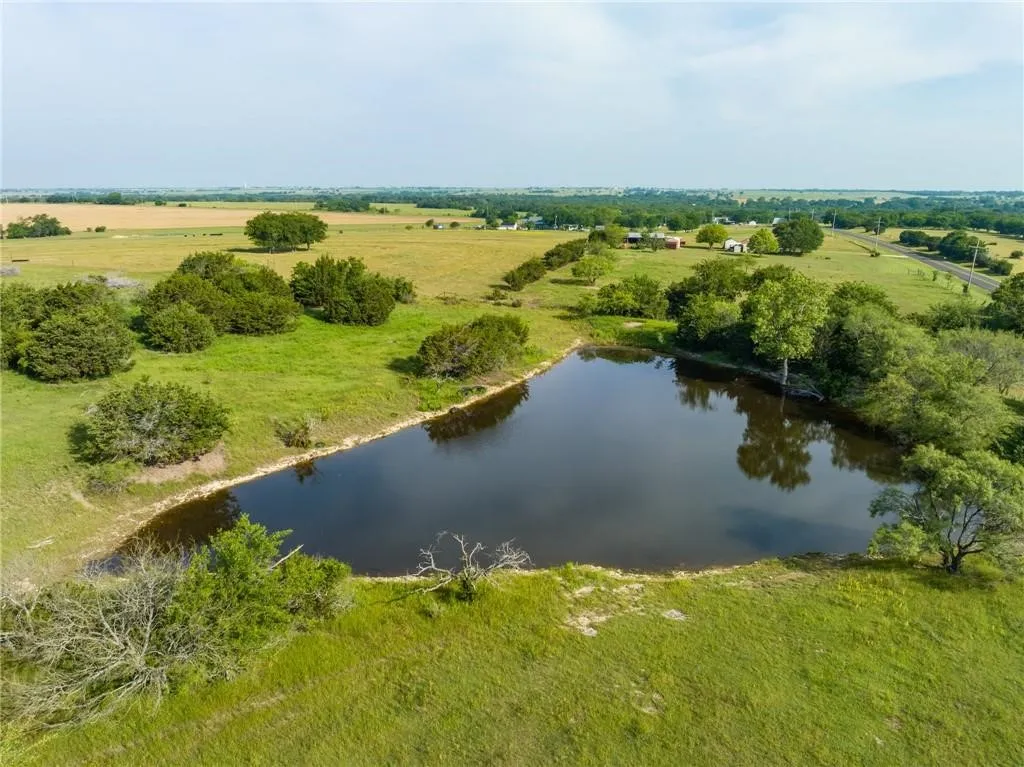 Expansive land featuring a large pond and surrounding greenery