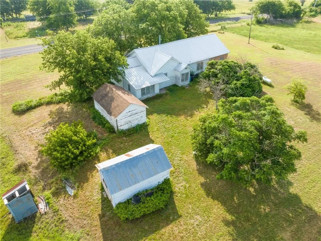 Expansive property featuring a residence with a metal roof, accompanied by two outbuildings