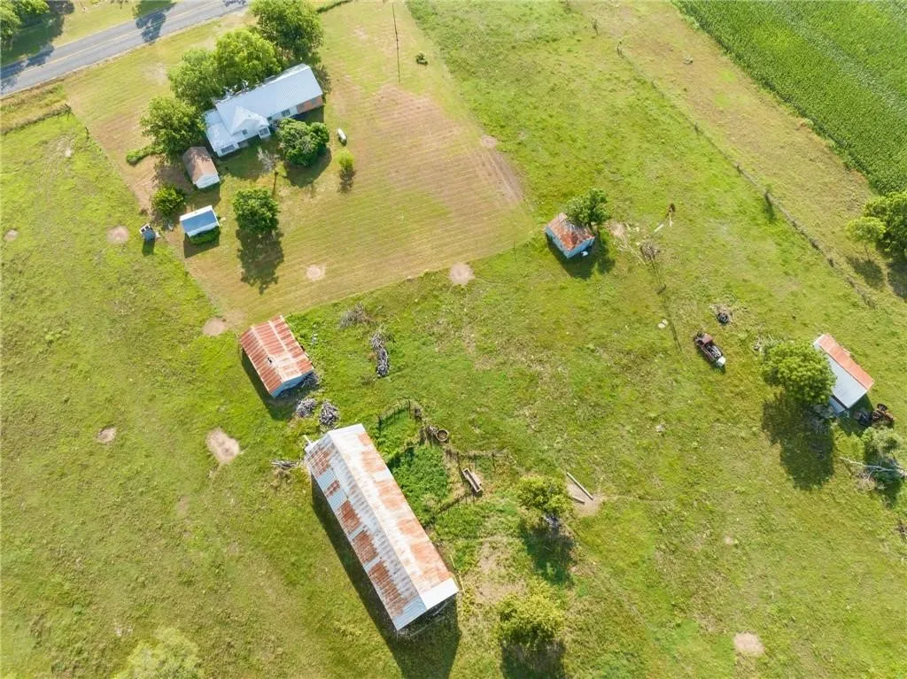 Expansive agricultural property featuring multiple outbuildings, mature trees, and direct road frontage