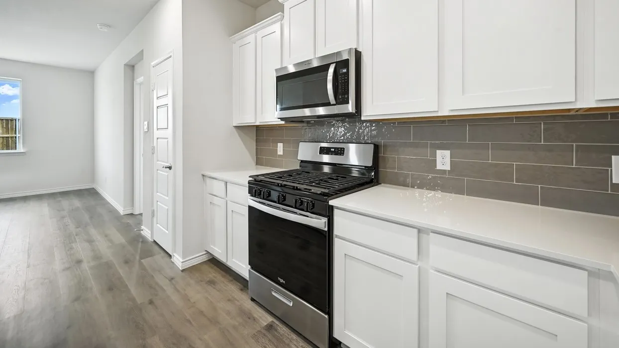 Modern kitchen featuring white shaker cabinetry, stainless steel appliances, light countertops, and a gray subway tile backsplash