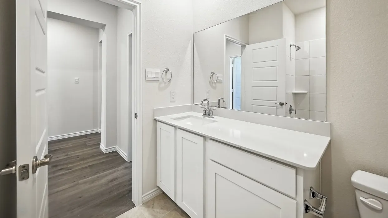 Bathroom featuring a white vanity with integrated sink, chrome fixtures, and a large wall-mounted mirror