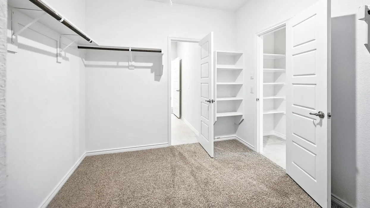 Carpeted room with a built-in closet system featuring a hanging rod and shelving