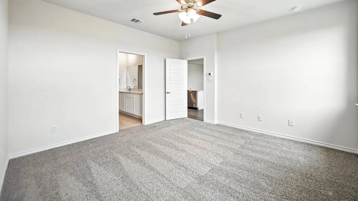 Spacious room featuring neutral carpeting, white walls, and a ceiling fan with integrated lighting