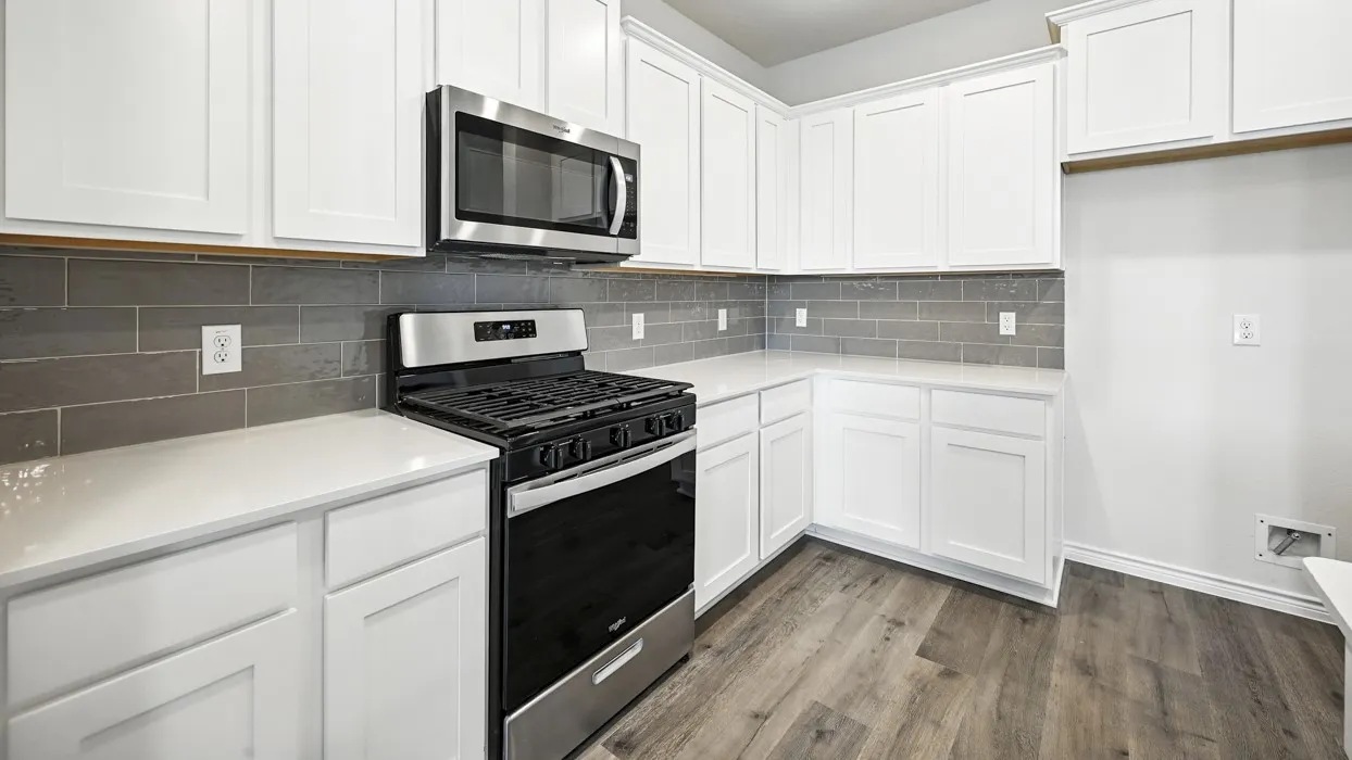 Kitchen featuring white cabinetry, light-toned countertops, a stainless steel microwave, a stainless steel and black range, and gray subway tile backsplash