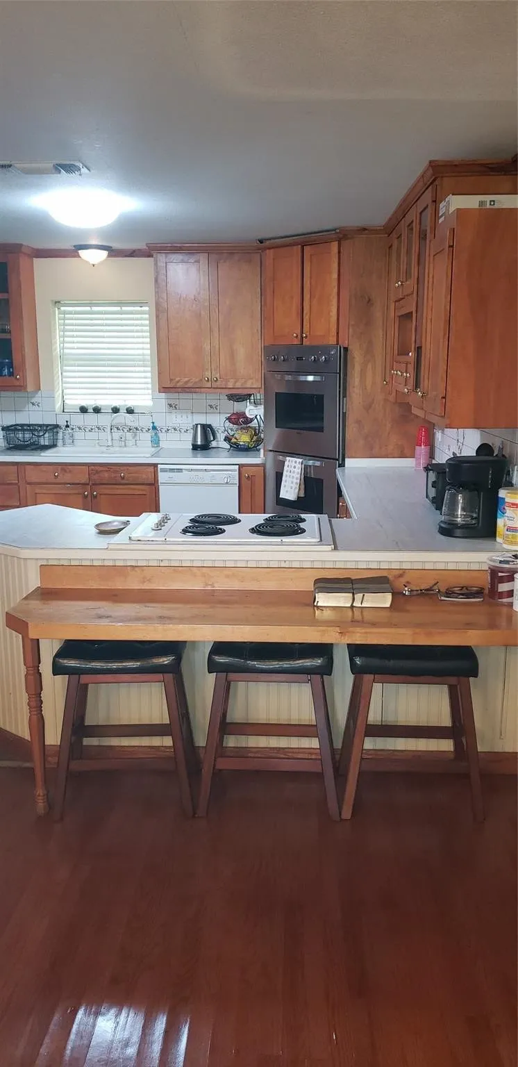 Kitchen featuring double oven, dishwasher, and dark wood-type flooring