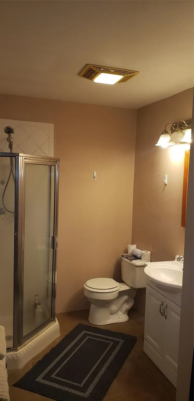 Bathroom with vanity, walk in shower, and toilet