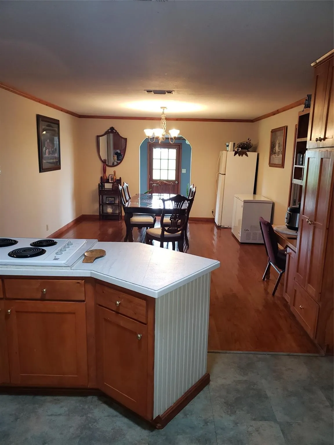 Kitchen with an inviting chandelier, crown molding, wood-type flooring, and white appliances