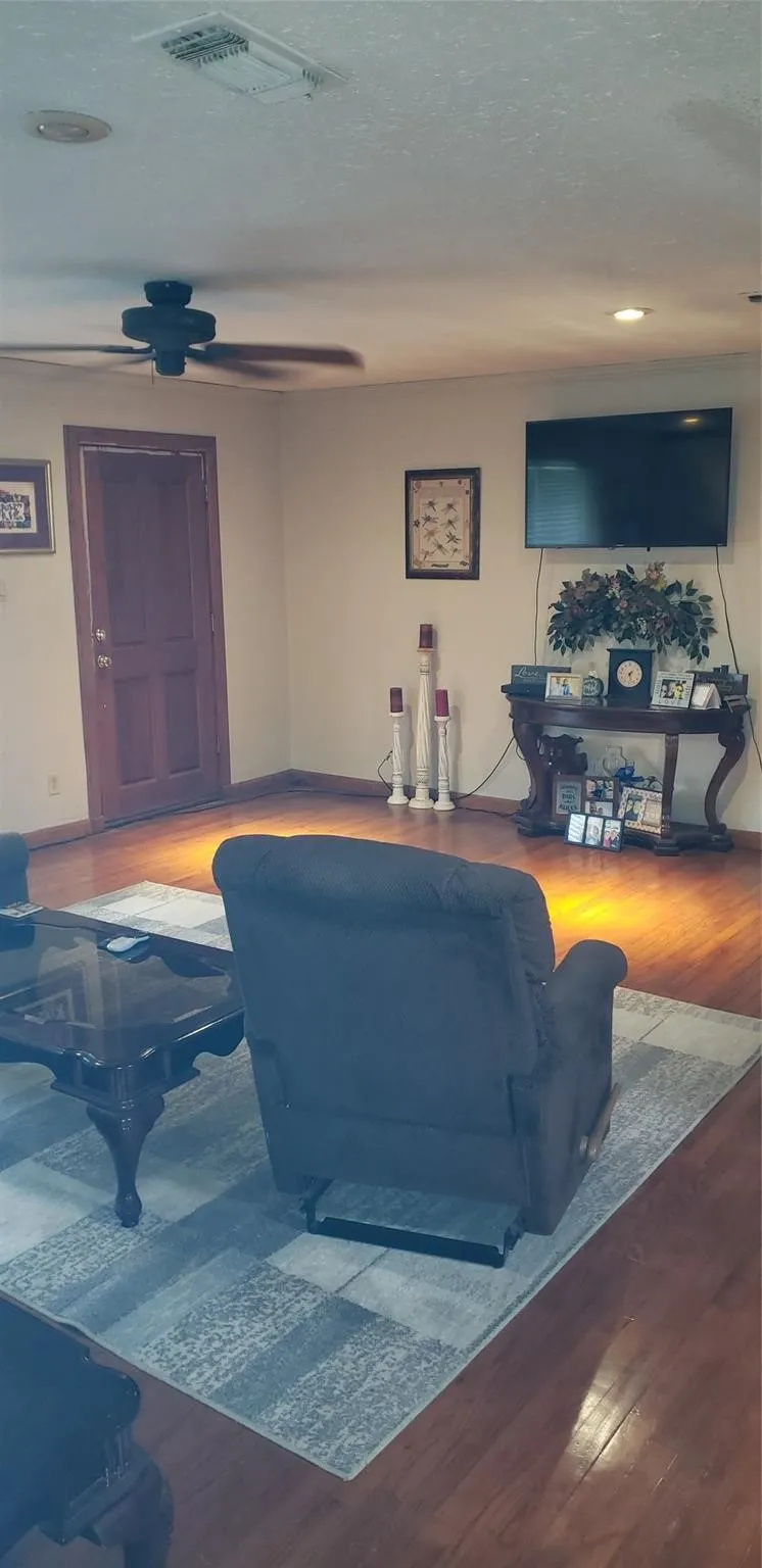 Living room featuring hardwood / wood-style flooring, a textured ceiling, and ceiling fan