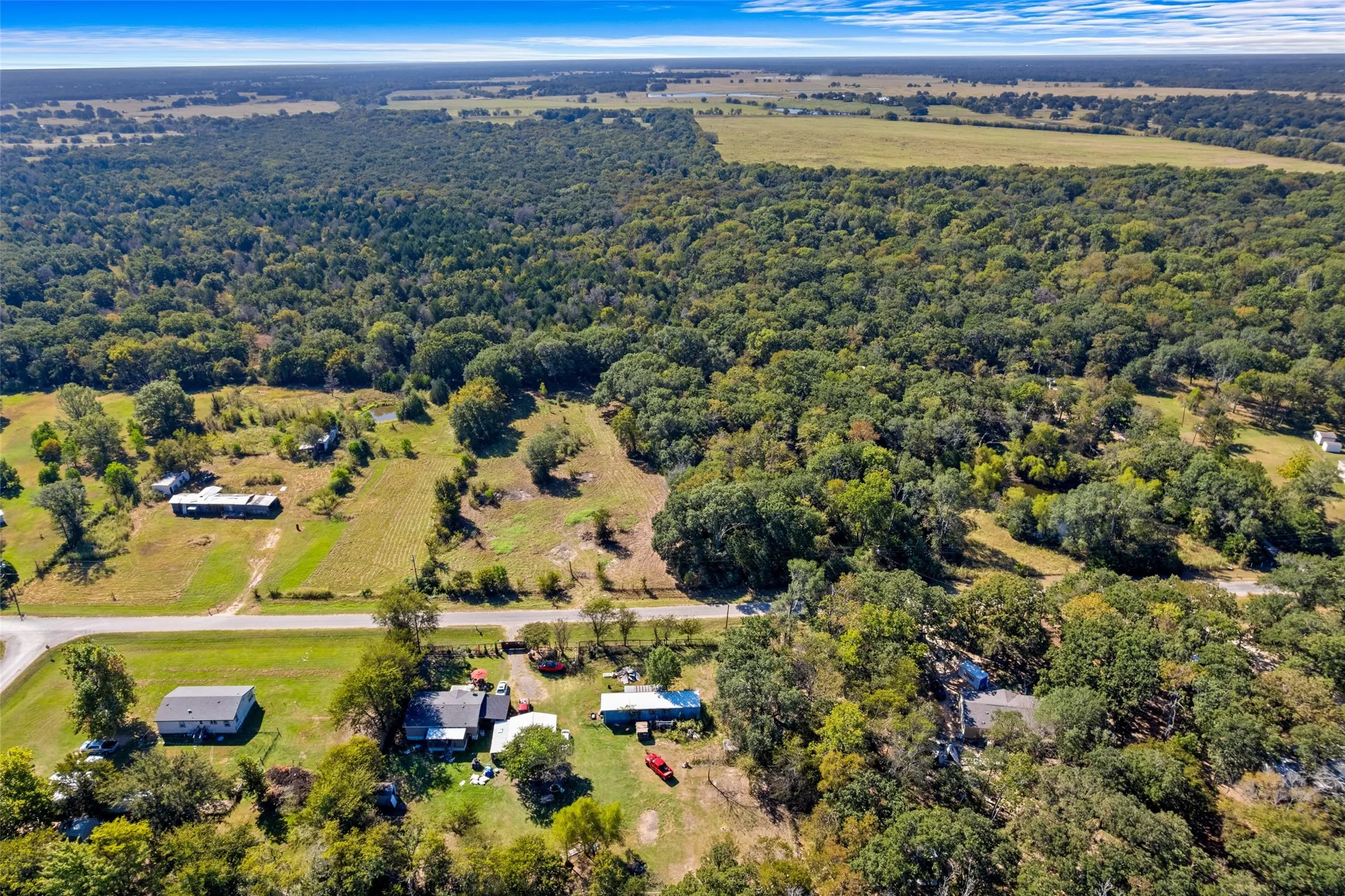 Expansive rural landscape featuring a mix of mature woodland and open fields