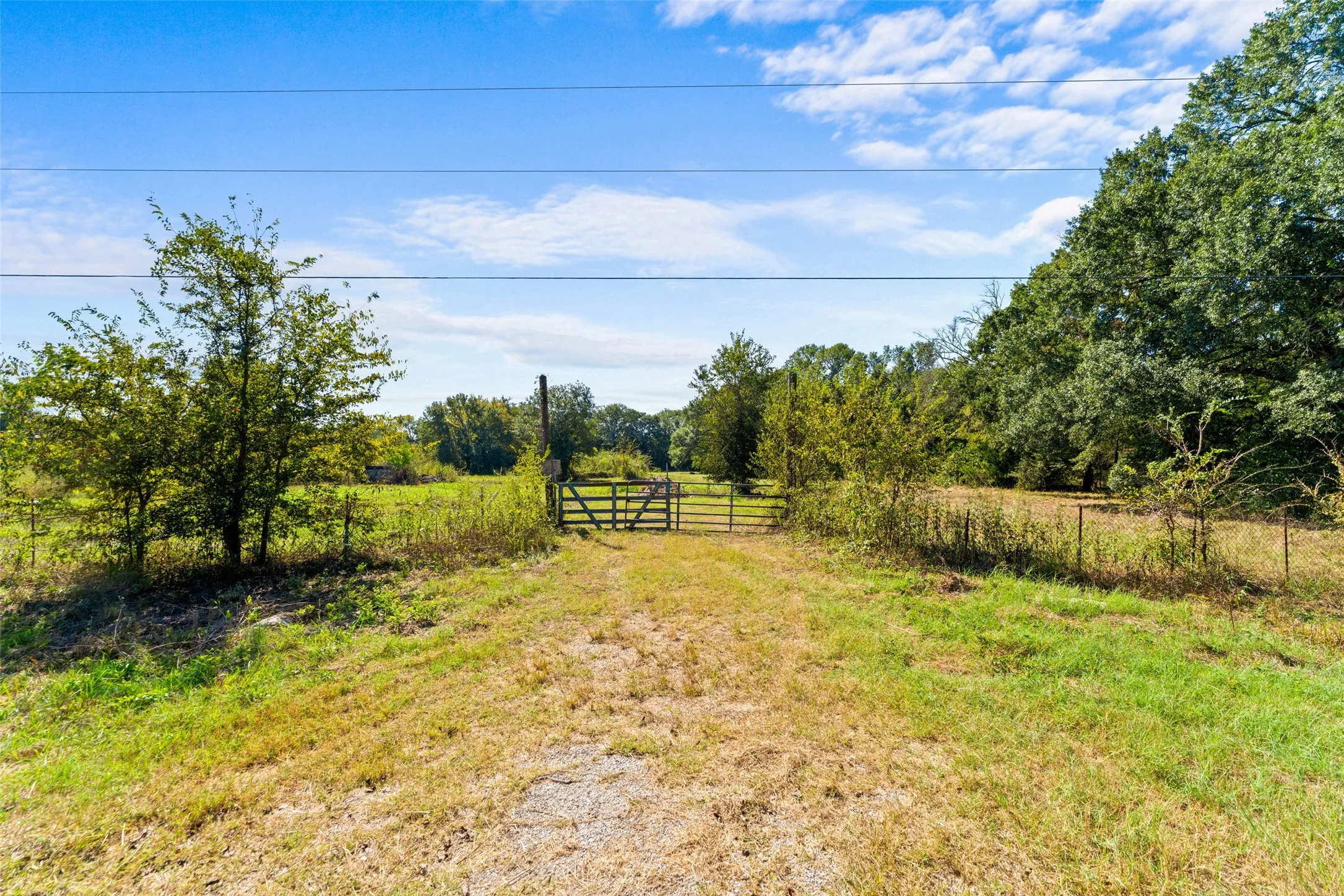 Gated entry to a expansive natural landscape with a gravel pathway