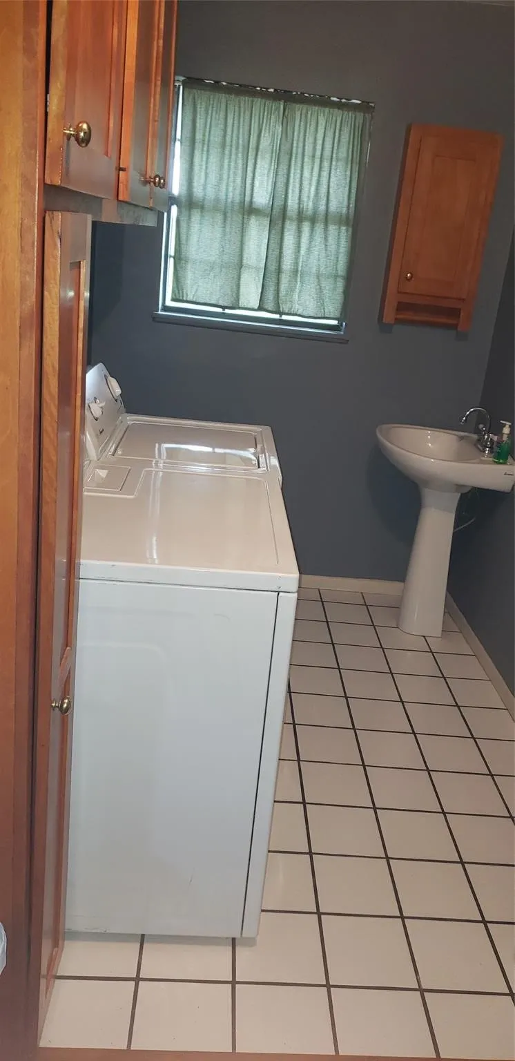Washroom with independent washer and dryer and light tile patterned floors