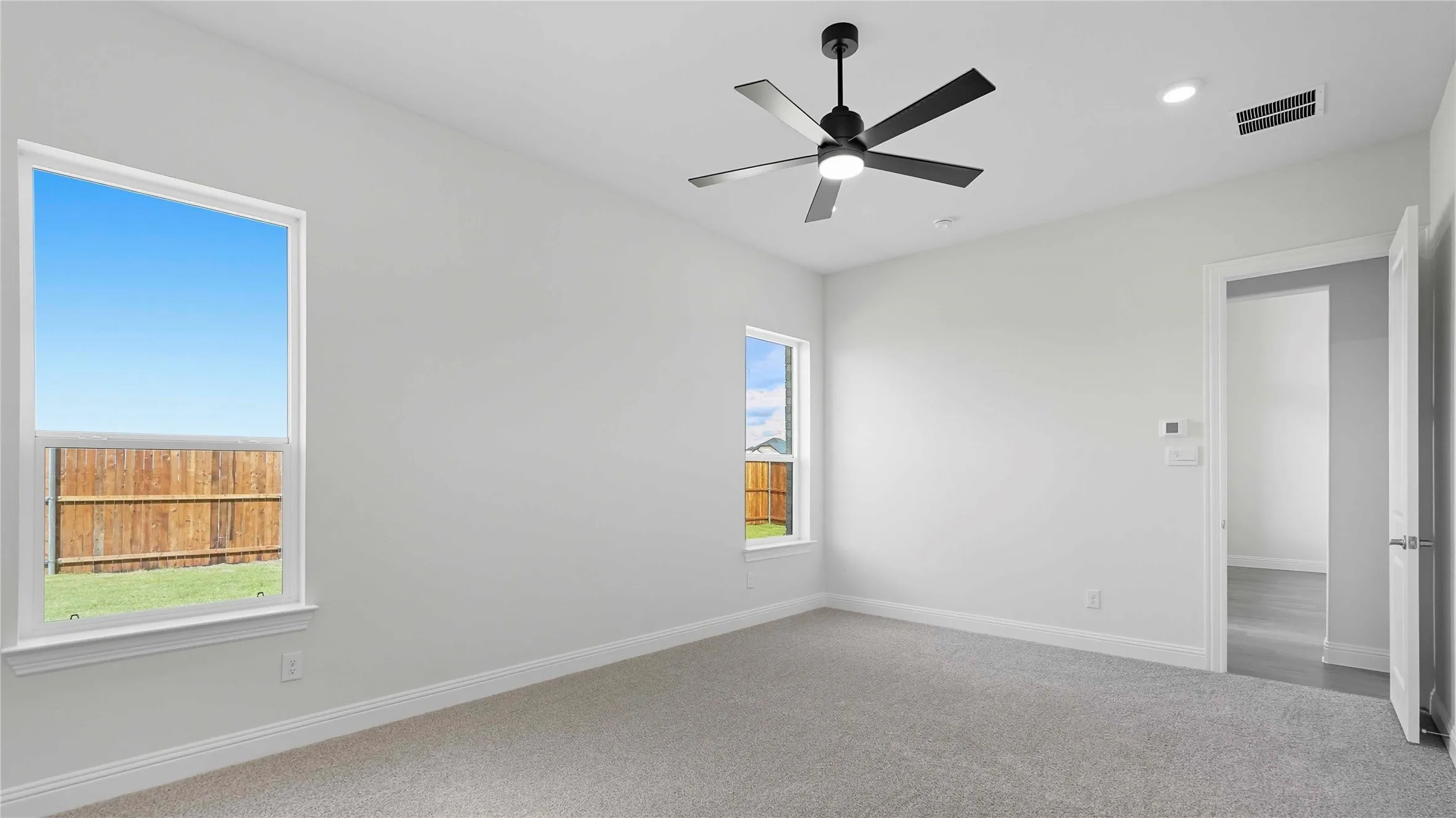 Spacious room featuring light gray carpet flooring and white walls