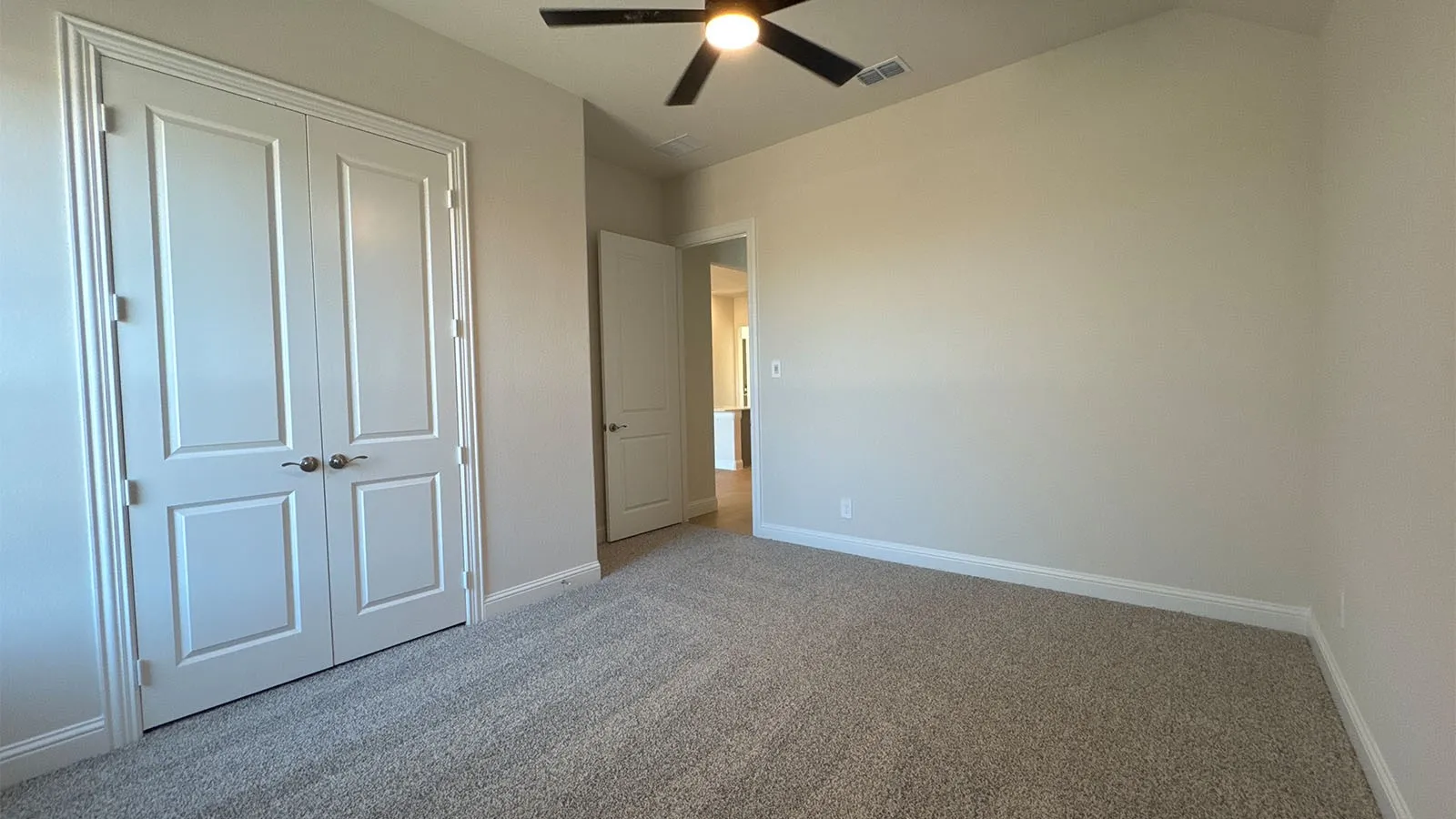 Carpeted room featuring a ceiling fan, double panel doors, and neutral wall tones