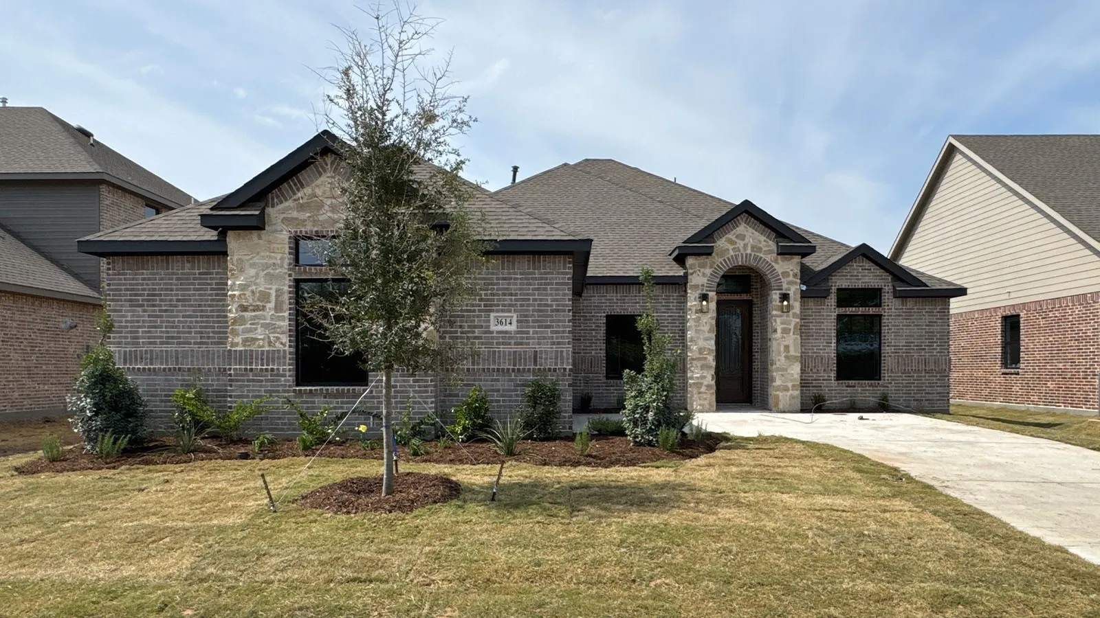 Brick and stone exterior with dark trim and an arched entryway