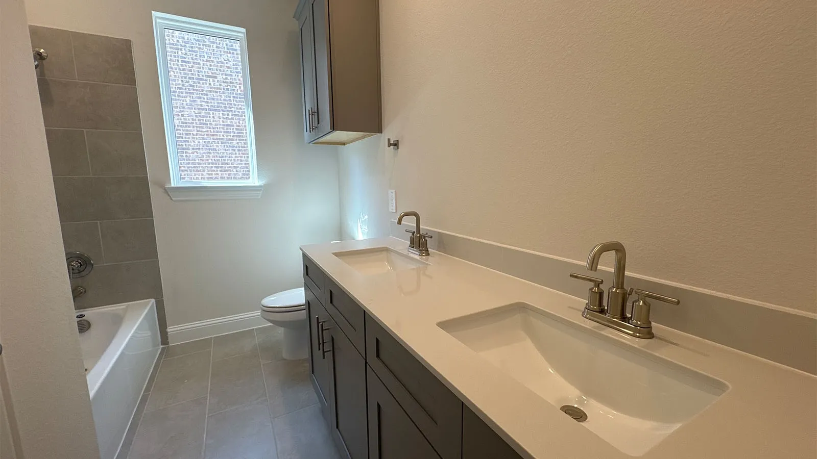 Double vanity with integrated sinks, brushed nickel fixtures, white countertop, and dark wood-finish cabinetry