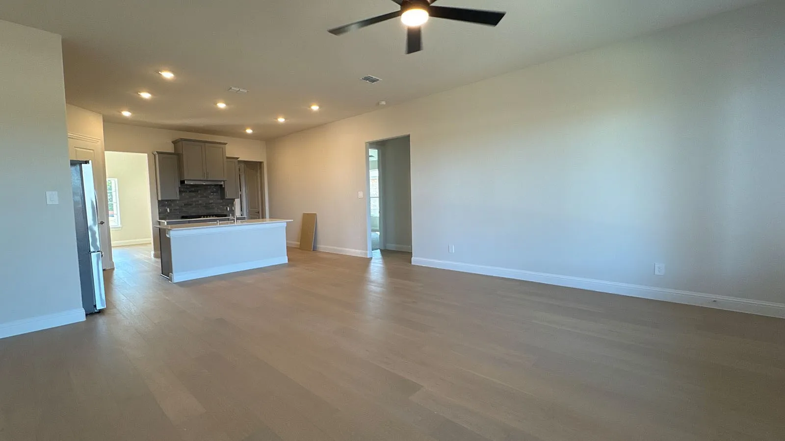 Open-concept living area with wood-finish flooring, recessed lighting, and a ceiling fan