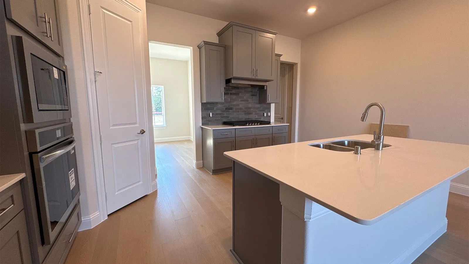 Kitchen featuring an island with a double basin sink, stainless steel faucet, and light-toned countertop