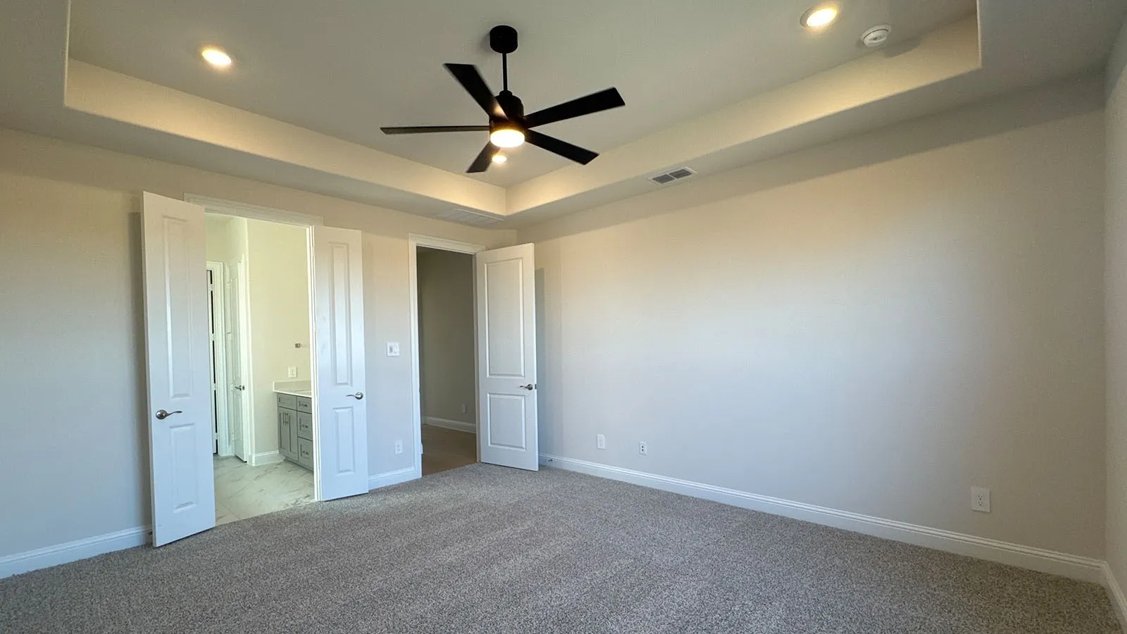 Tray ceiling with recessed lighting and a ceiling fan, plush carpeting, and light-toned walls