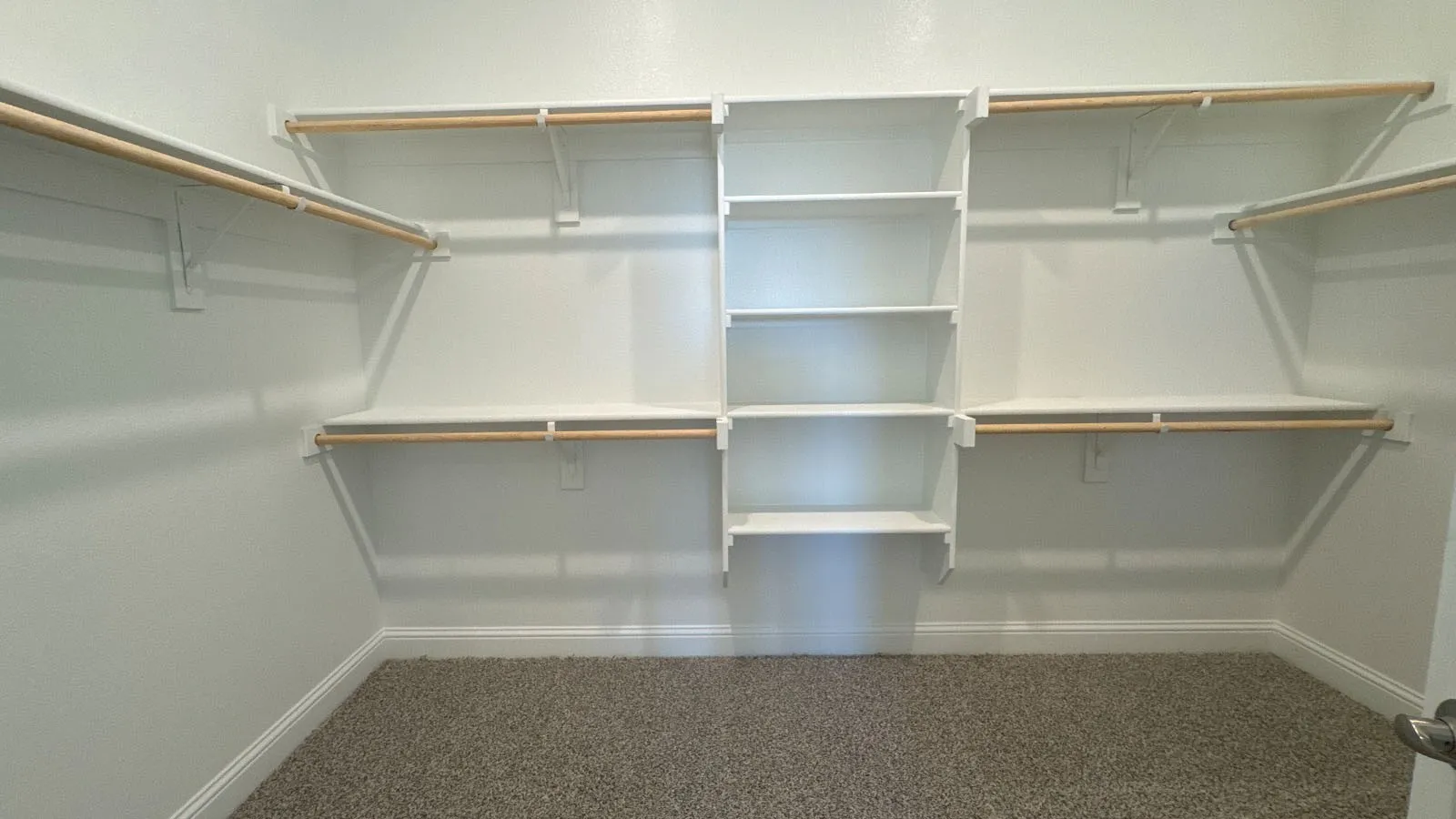 Walk-in closet featuring built-in shelving, multiple hanging rods, and neutral-toned carpeting