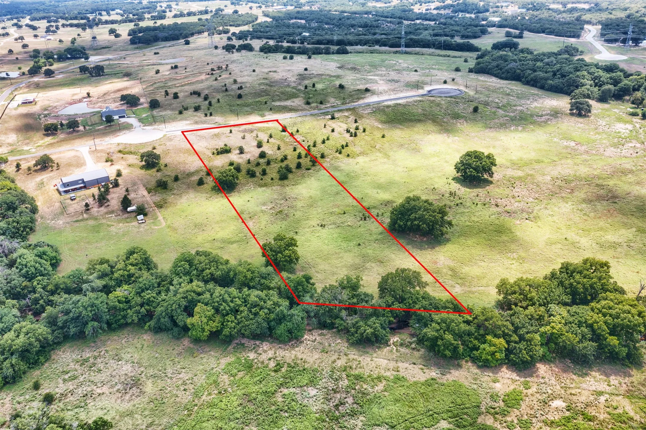 Expansive land parcel featuring a mix of open grassy areas and clusters of trees