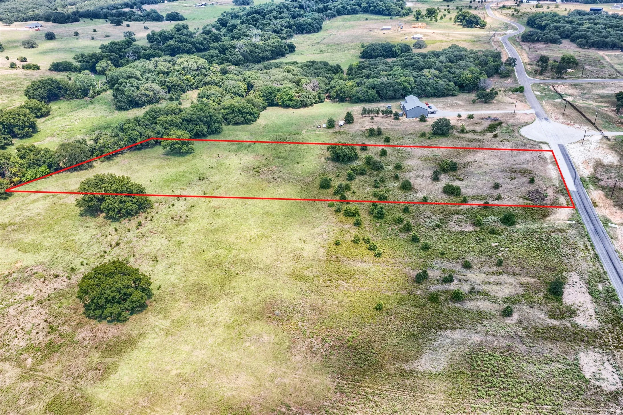 Expansive land parcel featuring a combination of open grassy areas and scattered mature trees