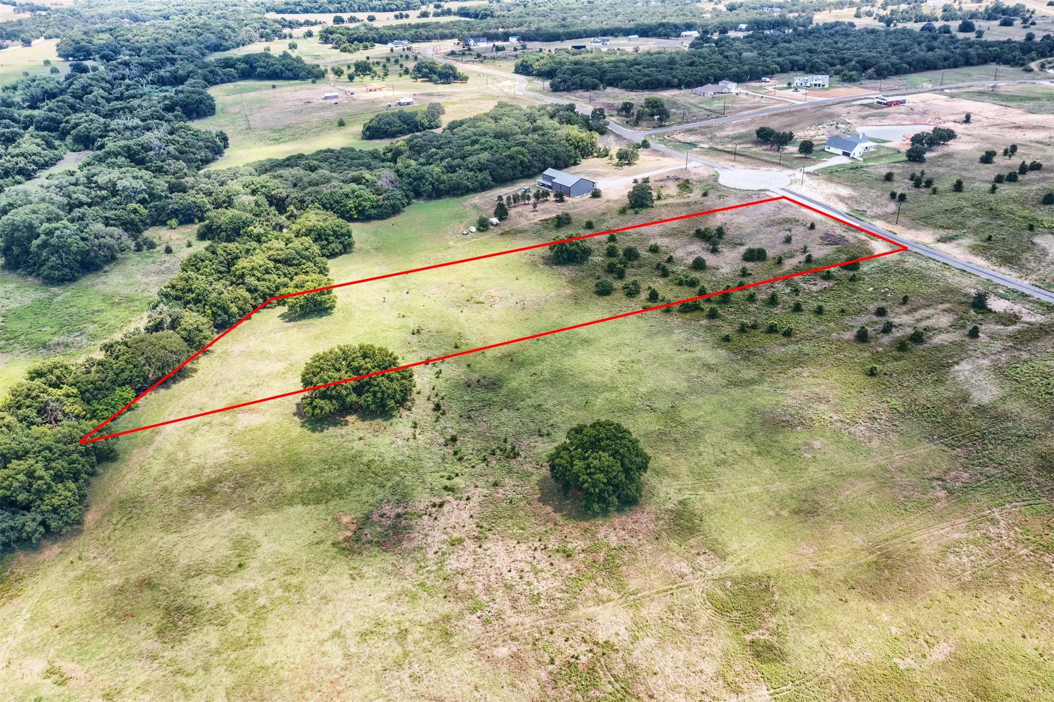 Expansive land parcel featuring open fields and mature tree lines
