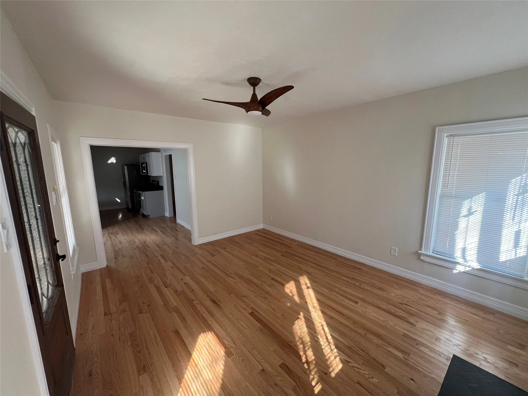 Unfurnished living room featuring ceiling fan and wood-type flooring